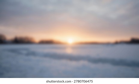 A soft focus image of a sunset over a snowy landscape. The colors are muted, with a range of oranges, pinks, and blues. The snow-covered ground is in the foreground, and the sun is setting in the distance.