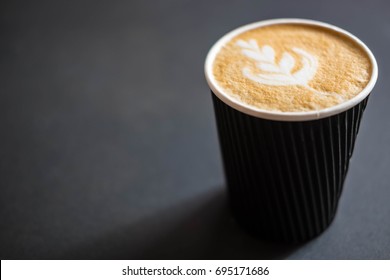 Soft Focus Of Latte Art Hot Coffee In Black Paper Cup On Gray Background With Shadow , Blurred And Soft Focus Image