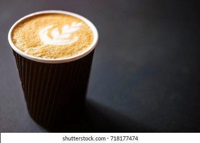 Soft Focus Of Latte Art Hot Coffee In Black Paper Cup On Gray Background With Shadow , Blurred And Soft Focus Image