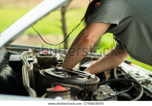 soft focus. man makes car repair under the hood.\
street repair