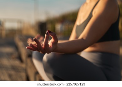 Soft focus on hand of faceless female with Gyan mudra sitting with legs crossed and concentrating on zen meditation sitting in sunlight - Shutterstock ID 2257027123