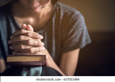 Soft focus hand woman while praying for christian religion and blurred her body background   Casual woman praying and her hands together over closed Bible