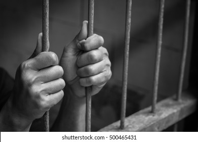 Soft focus on hands of man behind jail bars. vintage or retro style. selective focus. black and white image.