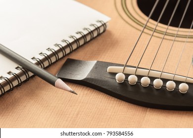 Soft Focus Of Pencil And Blank Notebook On Acoustic Guitar In Vintage Tone, Closeup.