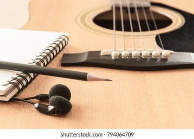 Soft Focus Of Pencil Blank Notebook And Earphone On Acoustic Guitar In Vintage Tone With Copy Space.