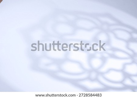 Soft focus rosette ring shadow on a cool white background with copy space