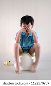 Soft Focus At Sad Little Asian Boy Sitting On The Potty Suffering From Stomach Ache.The Kid Put Yellow Toy Beside The Potty. Toilet Training Concept.