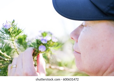 A Soft Focus Shot Of An Older Woman Smelling A Flower 