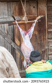 Soft Focus. Street Lighting. A Man With A Knife Removes The Skin From A Dead Animal. Rural Area