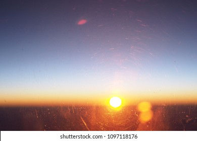 soft focus of sunset through a window’s plane with flare and scratches on window