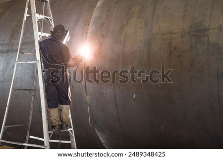 Soft focus of  technician is working welding steel .Welding machine with sparks and flashes. Worker and welder mending pipe metal at system assembled in gas and oil refinery plant.