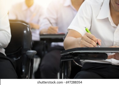 Soft Focus University Or High School Student Holding Pen.sitting On Row Chair Taking Final Exam In Examination Room Or Study In Classroom.student In Uniform.education Concept