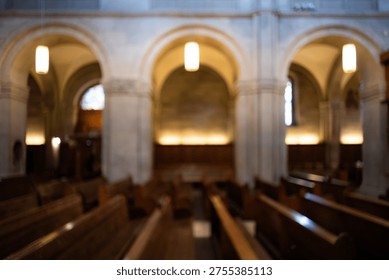 A soft focus view of a cathedral interior featuring massive stone arches and rows of wooden pews. Warm hanging lights and glowing wall lamps create a peaceful, serene atmosphere