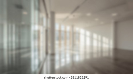 A soft focus view of a contemporary empty office space featuring glass partitions polished floors and bright daylight streaming through large windows for a professional background