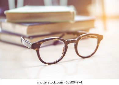 soft focus vintage glasses,blur books stack on wooden desk in university or public library room or book store,abstract book blur background.concept for education,background.