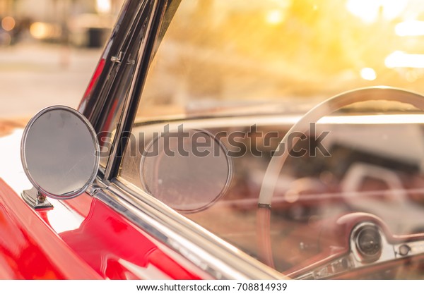Soft focus vintage mirror of a classic red\
car,round shape side\
mirror,