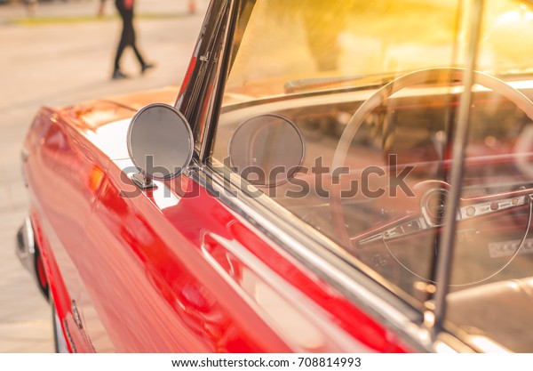 Soft focus vintage mirror of a classic red\
car,round shape side\
mirror,