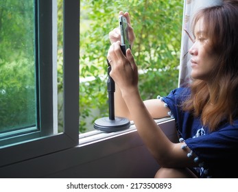 Soft Focus Woman With Smartphone In House With Window In Background   