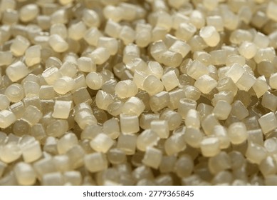 Soft focused translucent polymer granules create warm abstract background for manufacturing, recycling, packaging, and texture design.