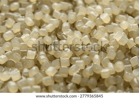 Soft focused translucent polymer granules create warm abstract background for manufacturing, recycling, packaging, and texture design.