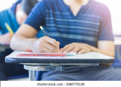 soft focus.hand high school or university student in casual holding pencil writing on paper answer sheet.sitting on lecture chair taking final exam attending in examination room or classroom.