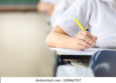 Soft Focus.high School Or University Student Holding Pencil Writing On Paper Answer Sheet.sitting On Lecture Chair Taking Final Exam Attending In Examination Room Or Classroom.student In Uniform