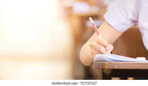 soft focus.high school or university student holding pencil writing on paper answer sheet.sitting on lecture chair taking final exam attending in examination room or classroom.student in uniform. - Shutterstock ID 717727117