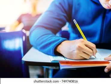 Soft Focus.high School Or University Student Holding Pencil Writing On Paper Answer Sheet.sitting On Lecture Chair Taking Final Exam Attending In Examination Room Or Classroom.