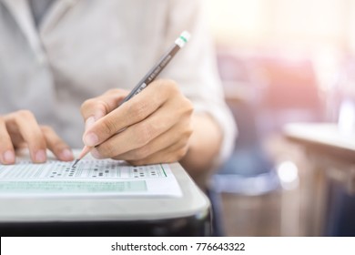 soft focus.high school or university student holding pencil writing on paper answer sheet.sitting on lecture chair taking final exam attending in examination room or classroom.student in casual