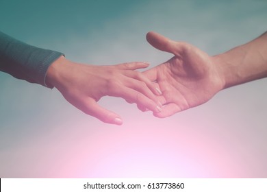 Soft, gentle touch of man and woman against sunny sky with flare in vintage mood. Love, connection, help concepts. Be hand in hand. two hands apart, reaching touching each other. Time concept.