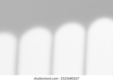 Soft gray background with a smooth texture. The background features blurred white light patterns, creating a calm gray ambiance. White minimal background. Window shadow on wall background.