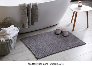 Soft grey mat with slippers on floor near tub in bathroom. Interior design - Shutterstock ID 2068656218