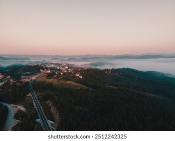 Soft hues of dawn envelop a tranquil village, surrounded by thick forests and rolling hills. A winding road leads into the misty horizon, inviting exploration of nature's beauty - Powered by Shutterstock