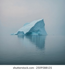 Soft Iceberg Afloat is a tranquil spectacle of nature's delicate artistry. Picture a colossal, yet gracefully undulating iceberg, its surface a smooth, ethereal blend of pale blues and frosted whites. - Powered by Shutterstock