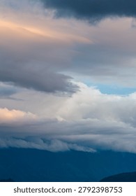 Soft layered clouds drift over misty blue mountains at sunrise, creating a calm, atmospheric scene near Chilliwack, British Columbia, Canada.