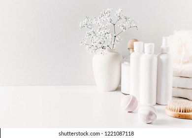Soft light bathroom decor for advertising, design, cover, set of cosmetic bottles, bath accessories, white small flowers in vase, towel on white wooden shelf. mock up,copy space
 - Shutterstock ID 1221087118