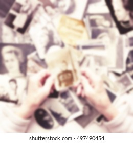 Soft light blurred background - Hands of the old woman which views her old photos. Vintage style image. 