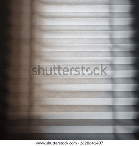 Soft light filtering through pleated window shade, creating minimal wave texture and calm shadow pattern — perfect for abstract or background use.