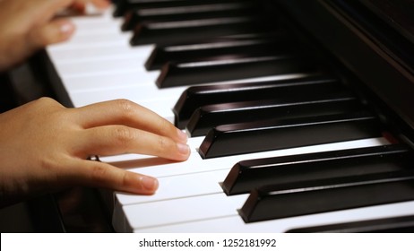 Soft, low light shot of Asian little girl practicing piano lesson at home - Powered by Shutterstock