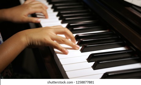 Soft, low light shot of Asian little girl practicing piano lesson at home - Powered by Shutterstock