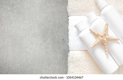 Soft modern bathroom decor for advertising, cover. Cosmetics bottles, towel, starfish, gray granite stone background. Flat lay, top view, copy space - Powered by Shutterstock