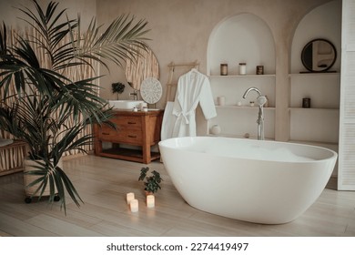 Soft native hues organic shapes look of bathroom with big window oval bathtub in neutrals tones. Green palm plants candles bubblebath leasure and relaxation skin selfcare wellness luxury living - Powered by Shutterstock