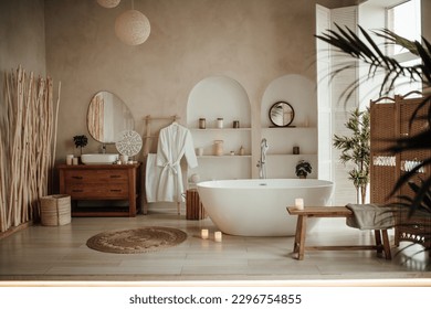 Soft native hues organic shapes look of bathroom with big window oval bathtub in neutrals tones. Green palm plants candles bubblebath leasure and relaxation skin selfcare wellness luxury living - Powered by Shutterstock