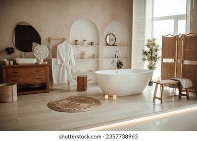 Soft native hues organic shapes look of bathroom with big window oval bathtub in neutrals tones. Green palm plants candles bubblebath leasure and relaxation skin selfcare wellness luxury living - Powered by Shutterstock