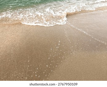 Soft ocean wave lapping on a sandy beach, providing a serene and calm atmosphere. Perfect for summer travel backgrounds and nature-inspired designs with copy space.