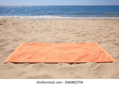 Soft Orange Beach Towel On Sandy Seashore