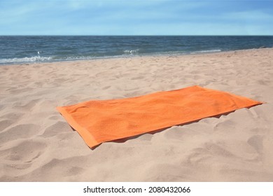 Soft Orange Beach Towel On Sandy Seashore