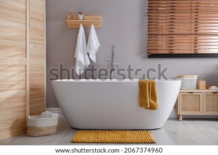 Soft orange mat on floor near tub in bathroom. Interior design