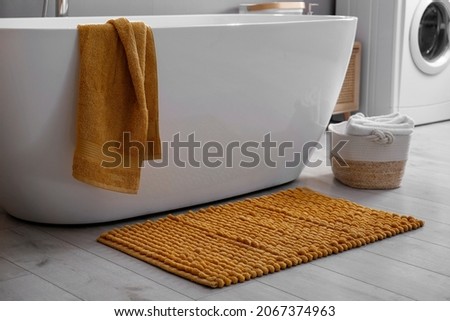 Soft orange mat on floor near tub in bathroom. Interior design