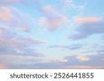 Soft pastel clouds drift across a bright blue sky during early morning or late afternoon in a tranquil landscape.